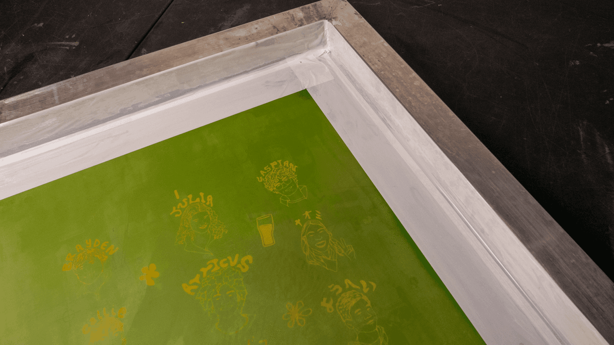 Squeegee pulling ink across a screen printing design