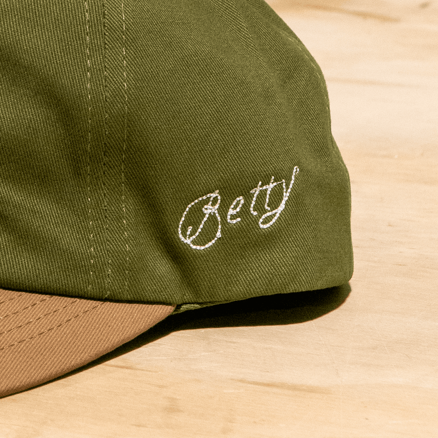 'Betty' embroidered in a cursive, chainstitch style on green ballcap'